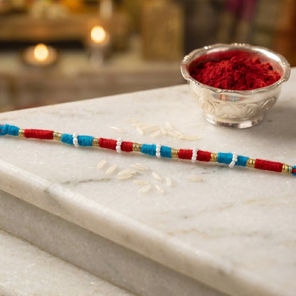 Decorative red rakhi thread bracelet with gold accents